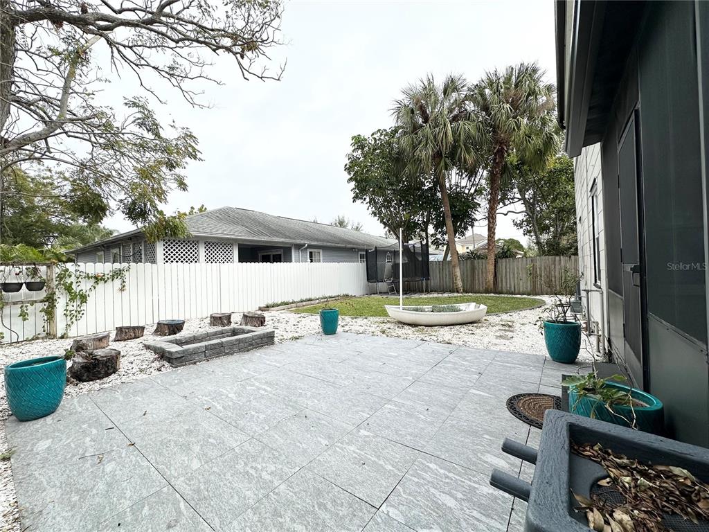 A backyard features a gray tiled patio, a stone fire pit, and a small boat — 3025 W NORTH A STREET, TAMPA, FL