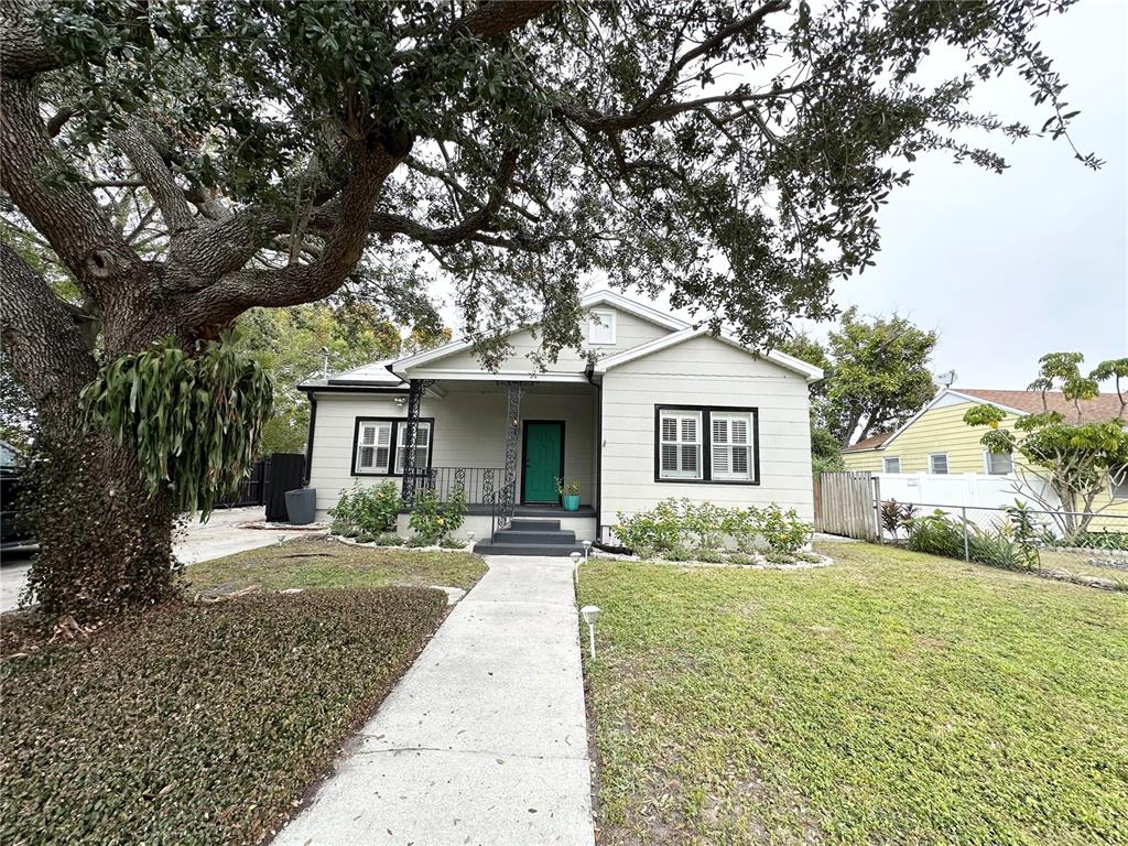 A single-story house with a green front door, black-trimmed windows, and a large oak tree — 3025 W NORTH A STREET, TAMPA, FL