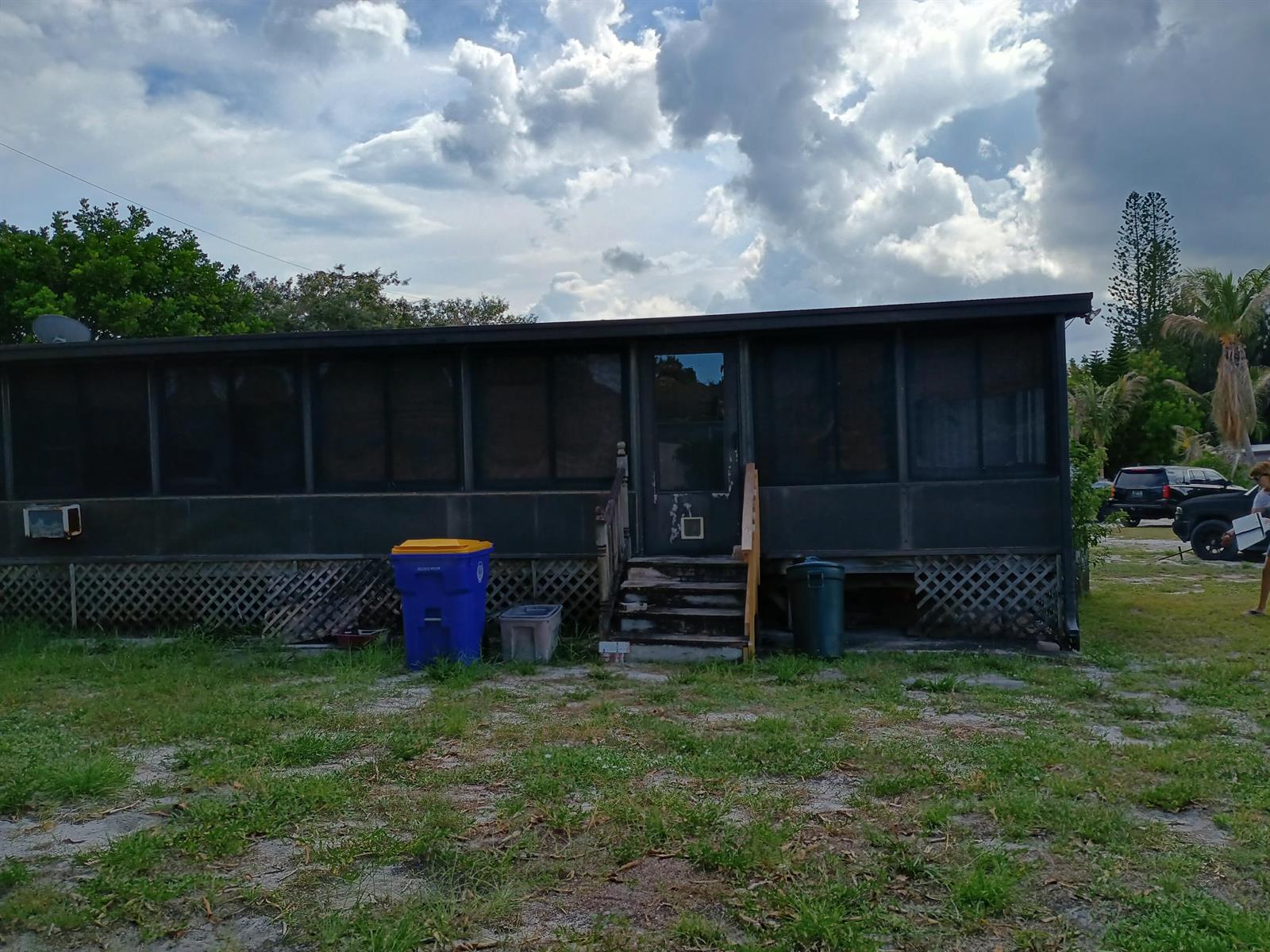 Exterior view of a single-story mobile home with a screened-in porch and lattice skirting — 7930 SE Cactus Trail, Hobe Sound FL 33455, HOBE SOUND, FL