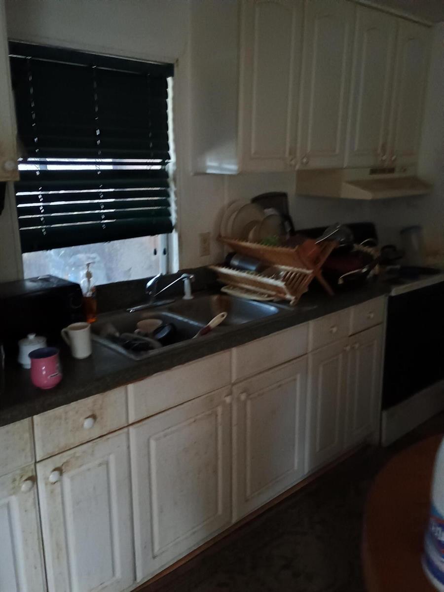 A kitchen features white cabinets, a double-basin sink, a window with blinds, and a stove — 7930 SE Cactus Trail, Hobe Sound FL 33455, HOBE SOUND, FL