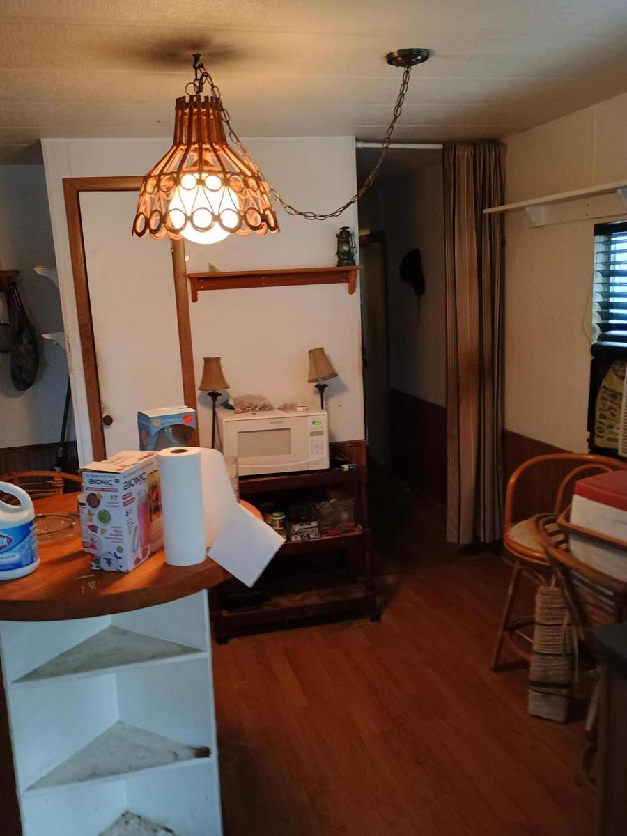 A kitchen area features a wooden pendant light, a microwave on a shelf, and wood flooring — 7930 SE Cactus Trail, Hobe Sound FL 33455, HOBE SOUND, FL