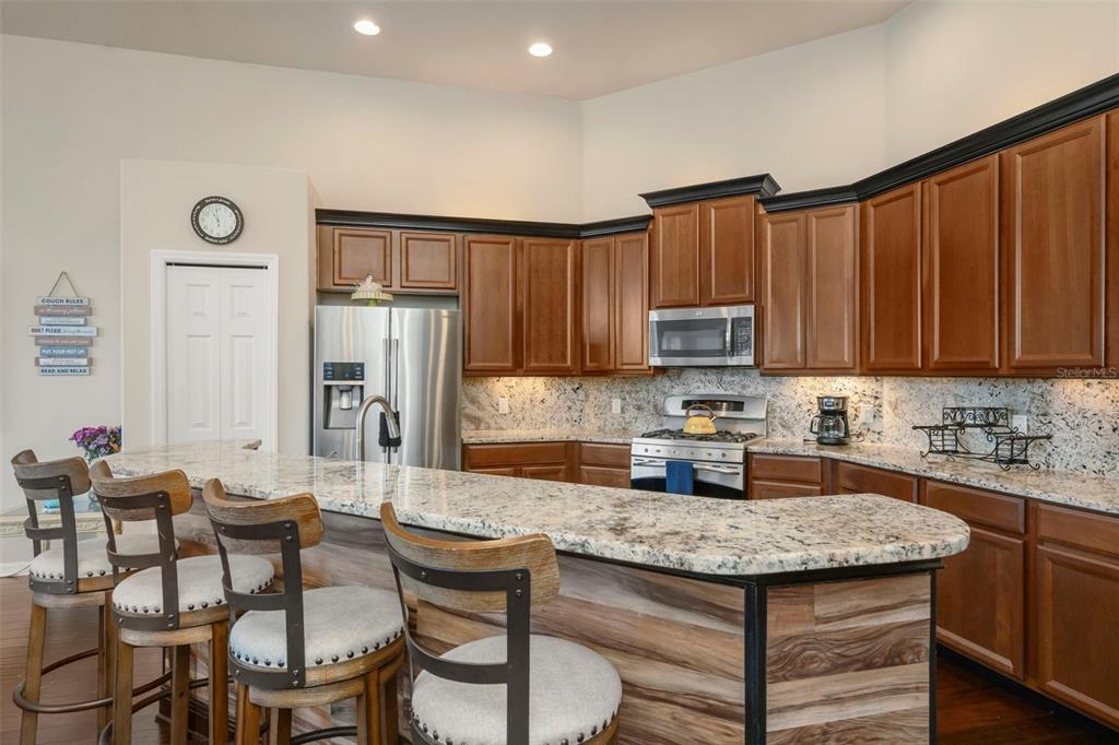 A kitchen features wood cabinets, granite countertops, stainless steel appliances, and a breakfast bar — 2307 SILVER TRUMPET COURT, VALRICO, FL