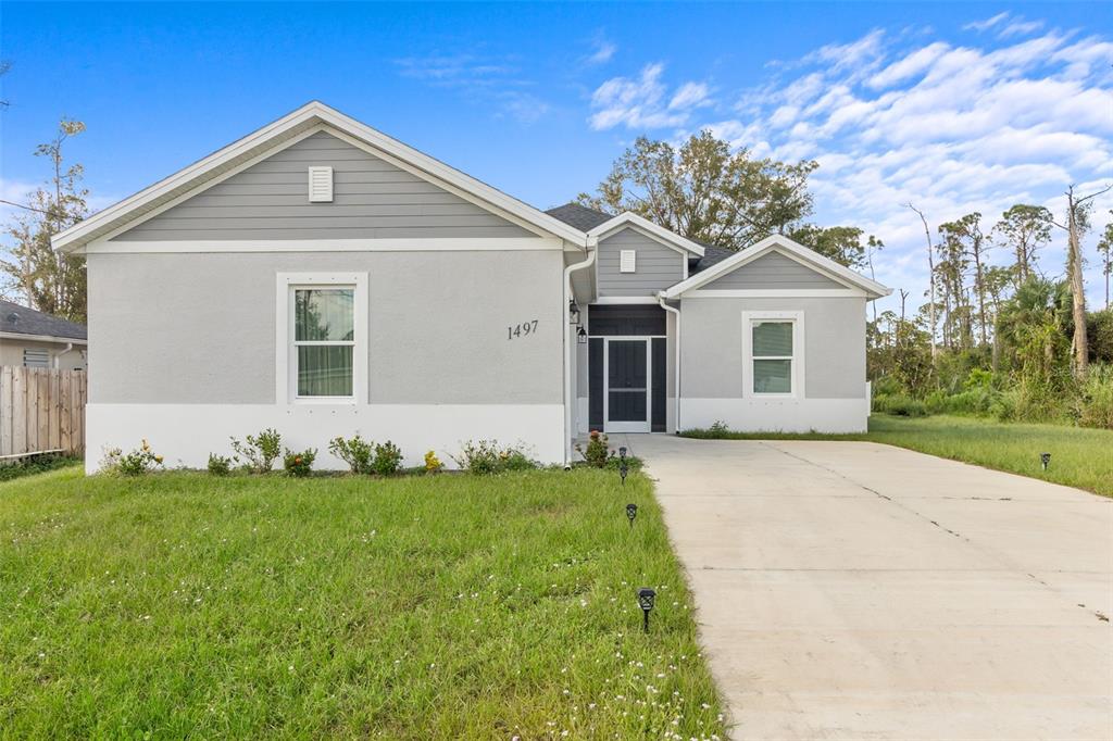 A single-story house with gray siding, a white stucco base, and a concrete driveway — 1497 NORDENDALE BOULEVARD, NORTH PORT, FL