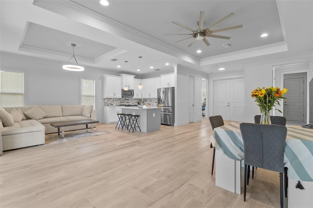 An open-concept living room and kitchen featuring light wood flooring, white cabinetry, and recessed lighting — 1497 NORDENDALE BOULEVARD, NORTH PORT, FL