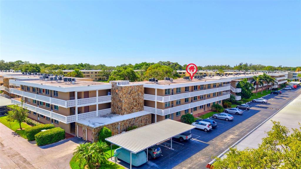 An aerial view shows a multi-story apartment complex with a stone facade and parking lot — 5095 BAY STREET NE UNIT 310, ST PETERSBURG, FL