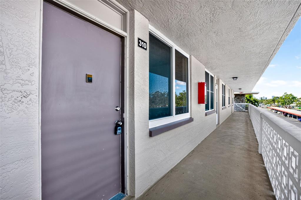 An exterior walkway leads to the entrance of apartment 310 with a purple door — 5095 BAY STREET NE UNIT 310, ST PETERSBURG, FL