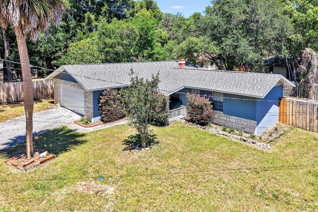 An elevated view of a single-story house with a blue exterior, stone accents, and driveway — 1709 NE 28TH PLACE, OCALA, FL
