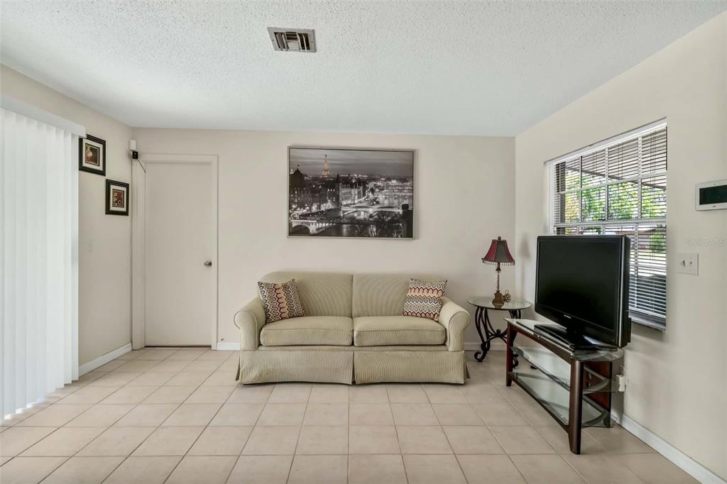 A living room features a beige sofa, a television on a stand, and tiled flooring — 1709 NE 28TH PLACE, OCALA, FL