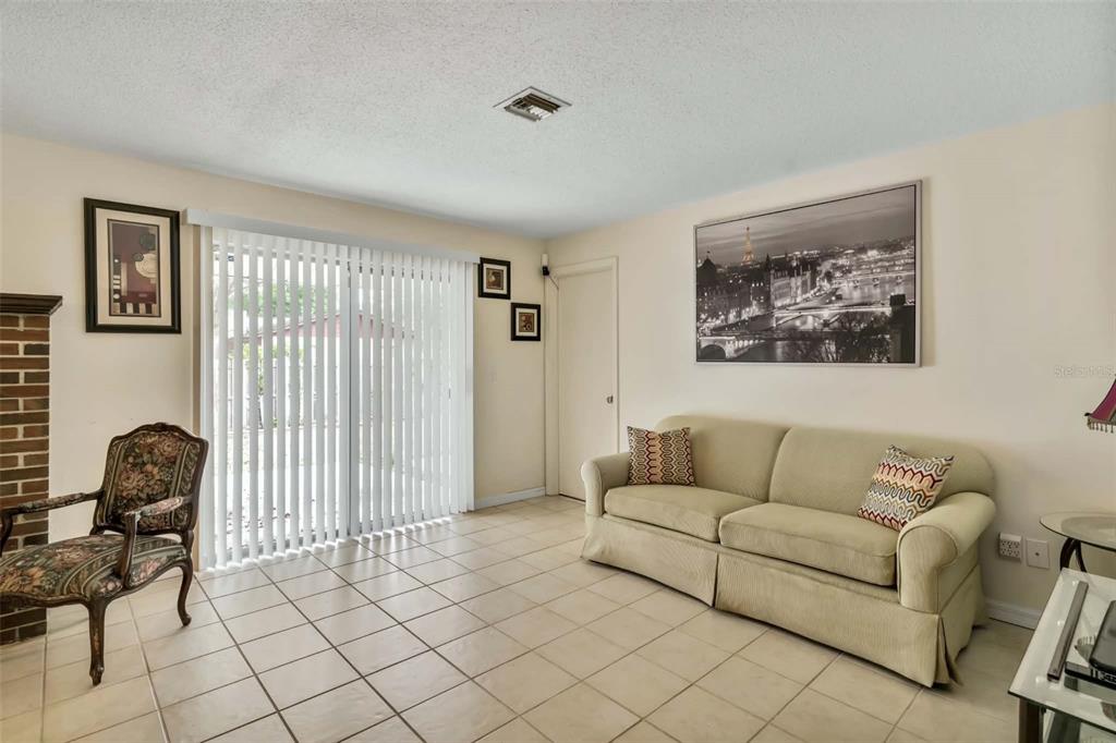 A living room features beige tile floors, a tan sofa, and a sliding glass door — 1709 NE 28TH PLACE, OCALA, FL
