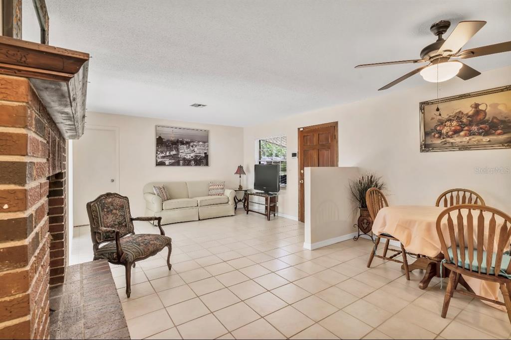 A living and dining area with tile floors, a brick fireplace, and a ceiling fan — 1709 NE 28TH PLACE, OCALA, FL