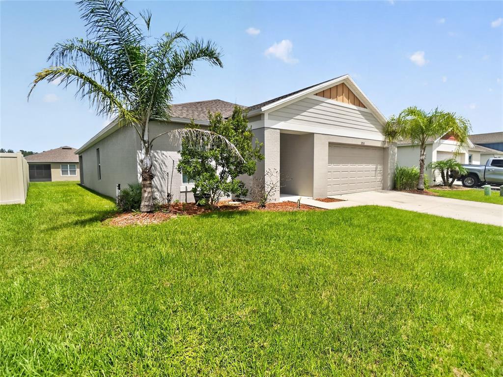 A single-story suburban house with a tan exterior, a two-car garage, and a palm tree — 5936 SLATE ROCK DRIVE, LAKELAND, FL