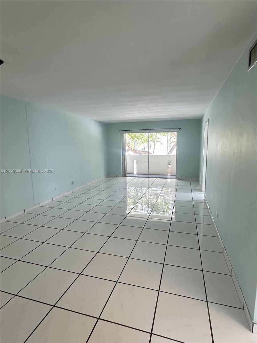 An empty room features light blue walls, white tiled floors, and a sliding glass door — 300 Galen Dr # 206, Key Biscayne FL 33149, KEY BISCAYNE, FL