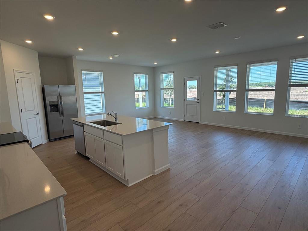 A modern kitchen with a central island and stainless steel appliances opens into a living area — 4377 VIBERNUM AVENUE UNIT A, ST CLOUD, FL
