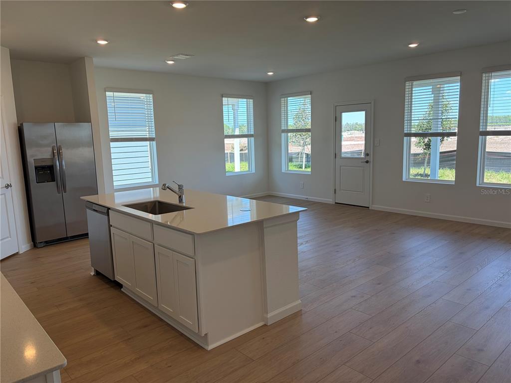 A kitchen island with a sink sits in an open-concept room with light wood floors — 4377 VIBERNUM AVENUE UNIT A, ST CLOUD, FL