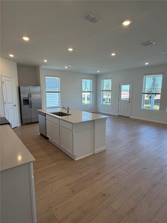 A kitchen with a central island, stainless steel appliances, and light wood-look flooring — 4377 VIBERNUM AVENUE UNIT A, ST CLOUD, FL