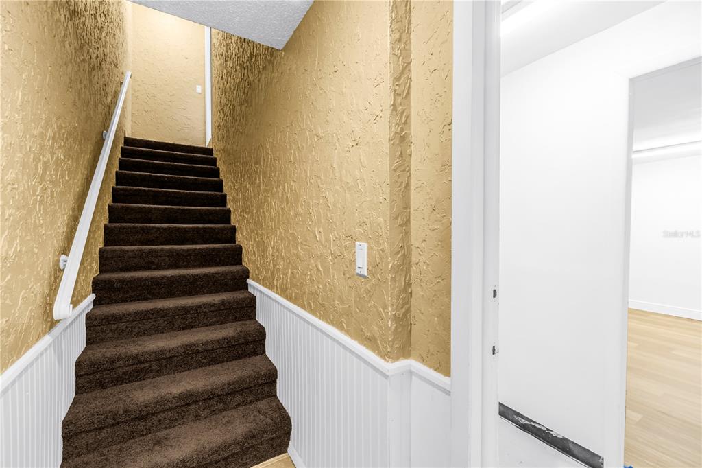 A staircase with dark brown carpeting and a white handrail leads to an upper level — 5403 SWEETWATER TERRACE CIRCLE UNIT 5403, TAMPA, FL
