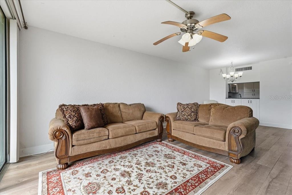 A living room features two brown sofas on a patterned rug with wood-look flooring — 2616 COVE CAY DRIVE UNIT 105, CLEARWATER, FL