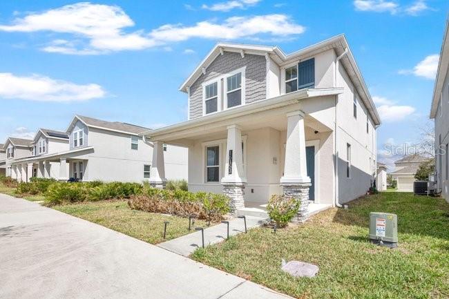 A two-story suburban house with a front porch and light-colored siding under a blue sky — 16153 WATER SPRING BOULEVARD, WINTER GARDEN, FL