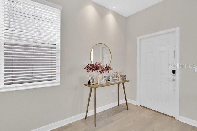 An entryway features a console table, a round mirror, and a white door — 16153 WATER SPRING BOULEVARD, WINTER GARDEN, FL