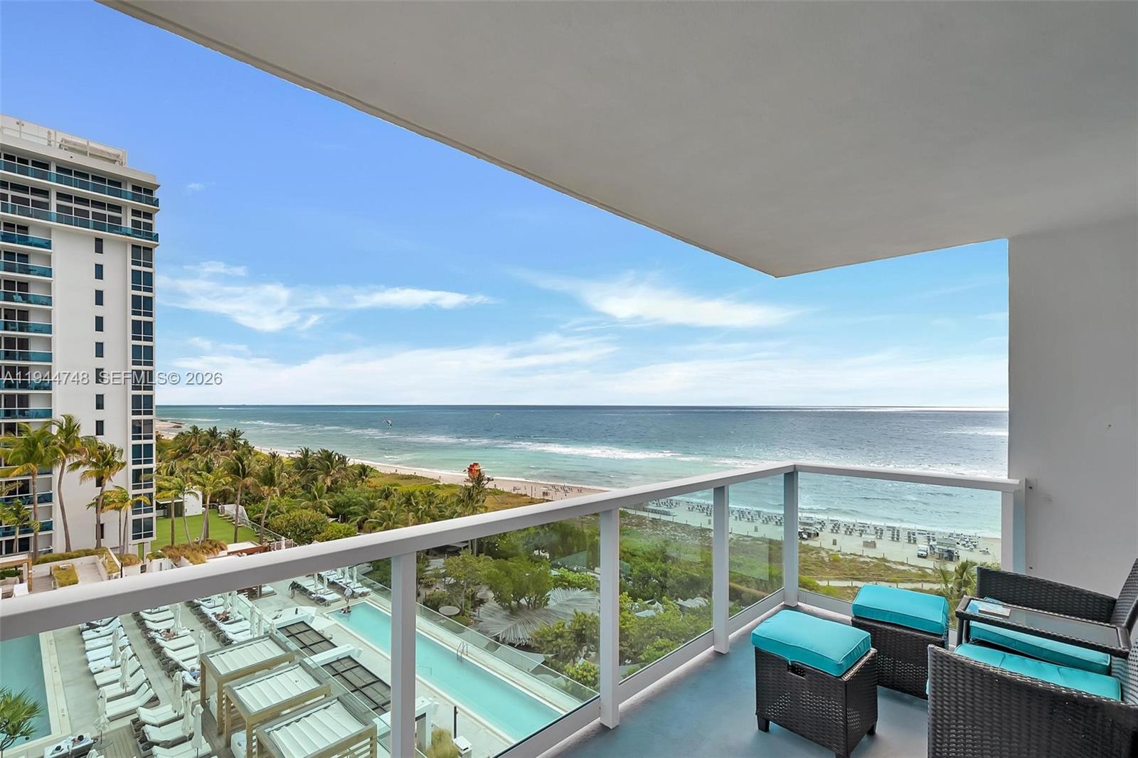 A balcony overlooks a swimming pool, palm trees, a sandy beach, and the ocean — 2301 Collins Ave # 810, Miami Beach FL 33139, MIAMI BEACH, FL