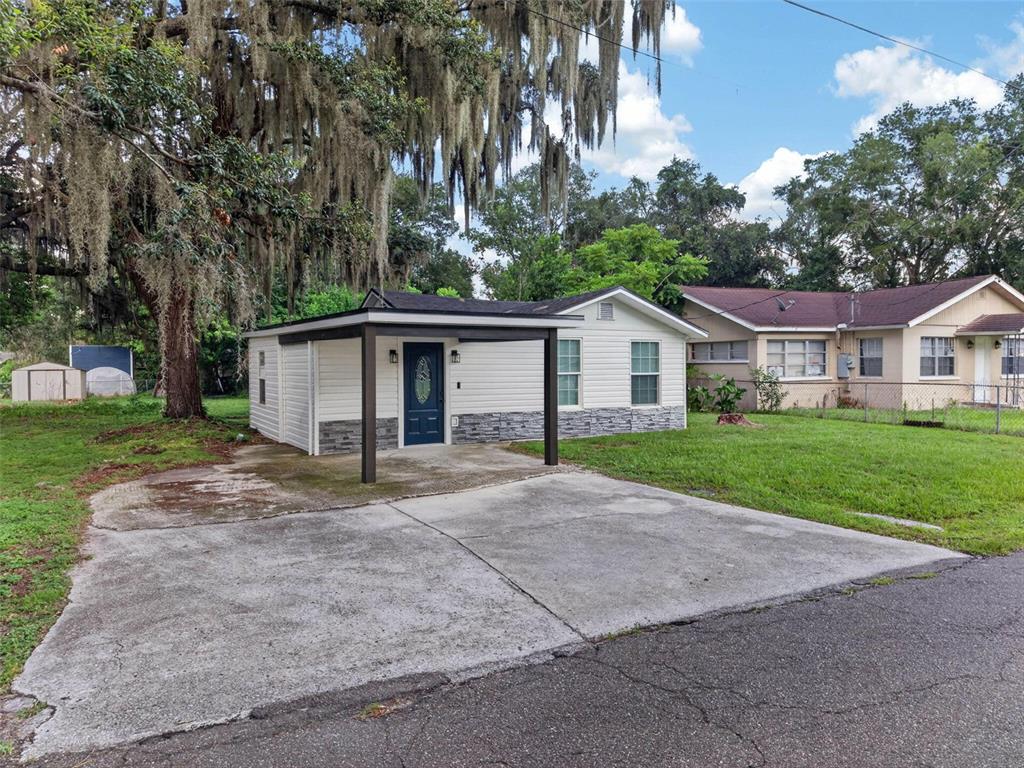 A small, single-story house with white siding, a stone base, and a front carport — 925 ADRIAN COURT, LAKELAND, FL
