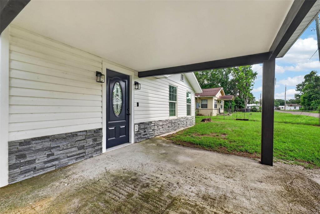 A covered concrete porch leads to a dark front door with a decorative glass insert — 925 ADRIAN COURT, LAKELAND, FL