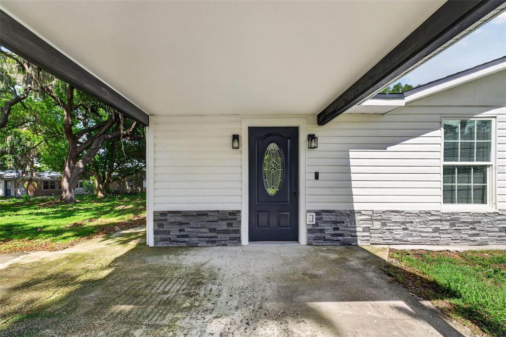 A covered concrete entryway features a dark front door with an oval glass insert — 925 ADRIAN COURT, LAKELAND, FL