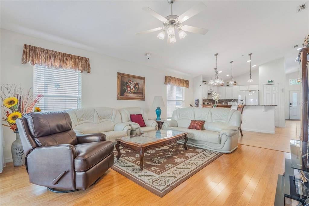 A living room with white leather sofas, a brown recliner, and an open-concept kitchen — 5389 WATERVISTA DRIVE, ORLANDO, FL