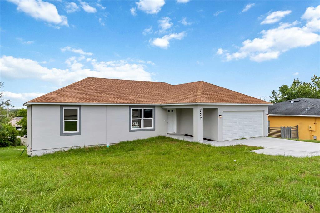 A single-story house with a light gray exterior, a brown shingled roof, and a garage — 2242 N NORMANDY BOULEVARD, DELTONA, FL