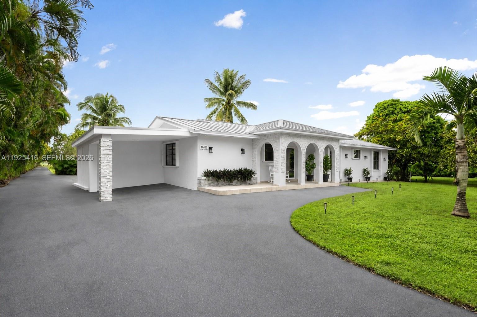 A white single-story house features a carport, arched entryway, and a circular asphalt driveway — 20450 SW 198th Ave, Miami FL 33187, MIAMI, FL