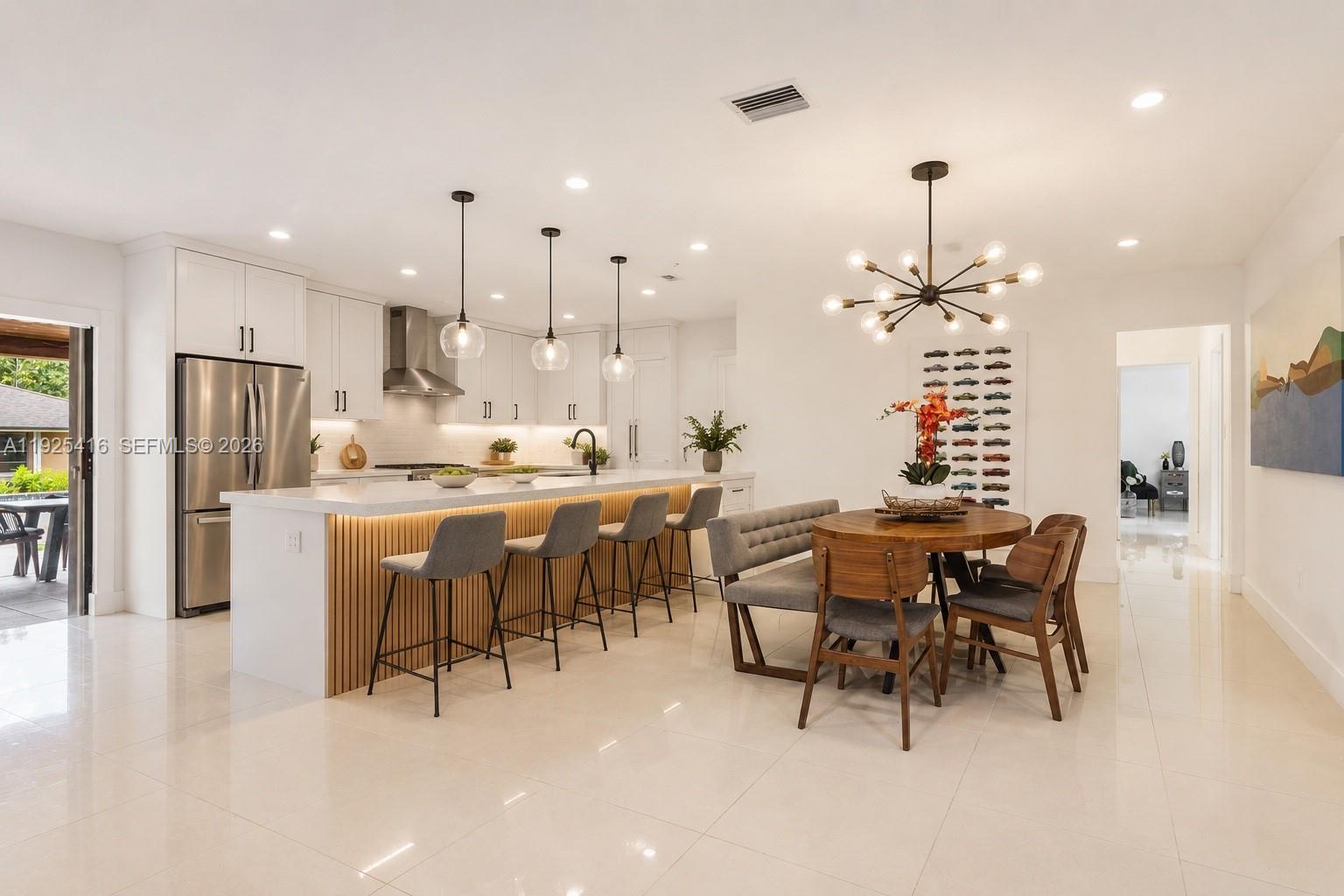 A modern kitchen features a large island with bar seating and an adjacent dining area — 20450 SW 198th Ave, Miami FL 33187, MIAMI, FL