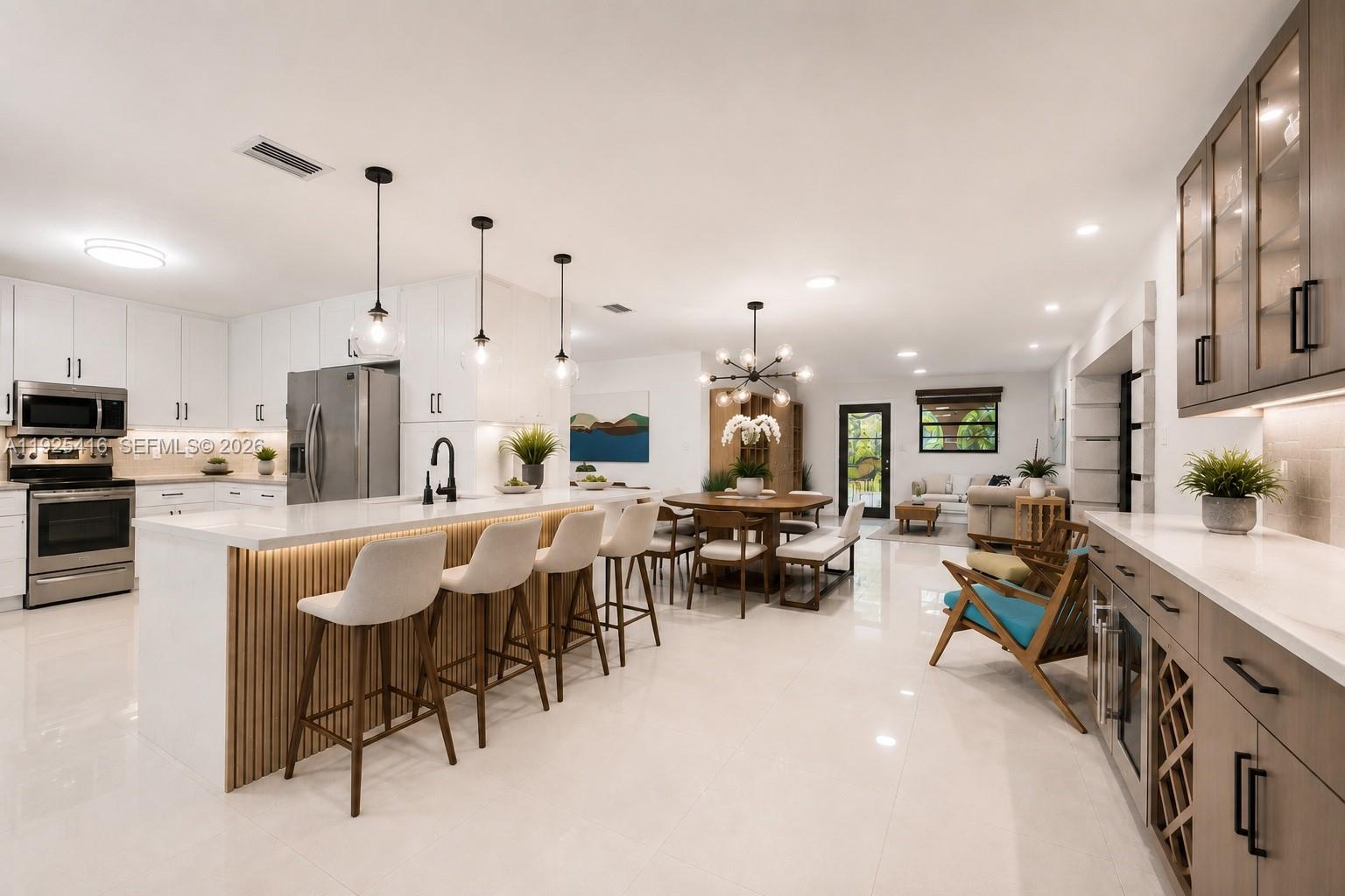 A modern open-concept kitchen features a large island with bar seating and white cabinetry — 20450 SW 198th Ave, Miami FL 33187, MIAMI, FL