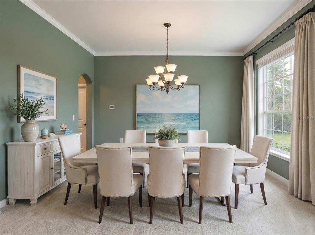 A dining room with sage green walls, a white table, upholstered chairs, and a chandelier — 7018 CARDINALWOOD LANE, LAND O LAKES, FL
