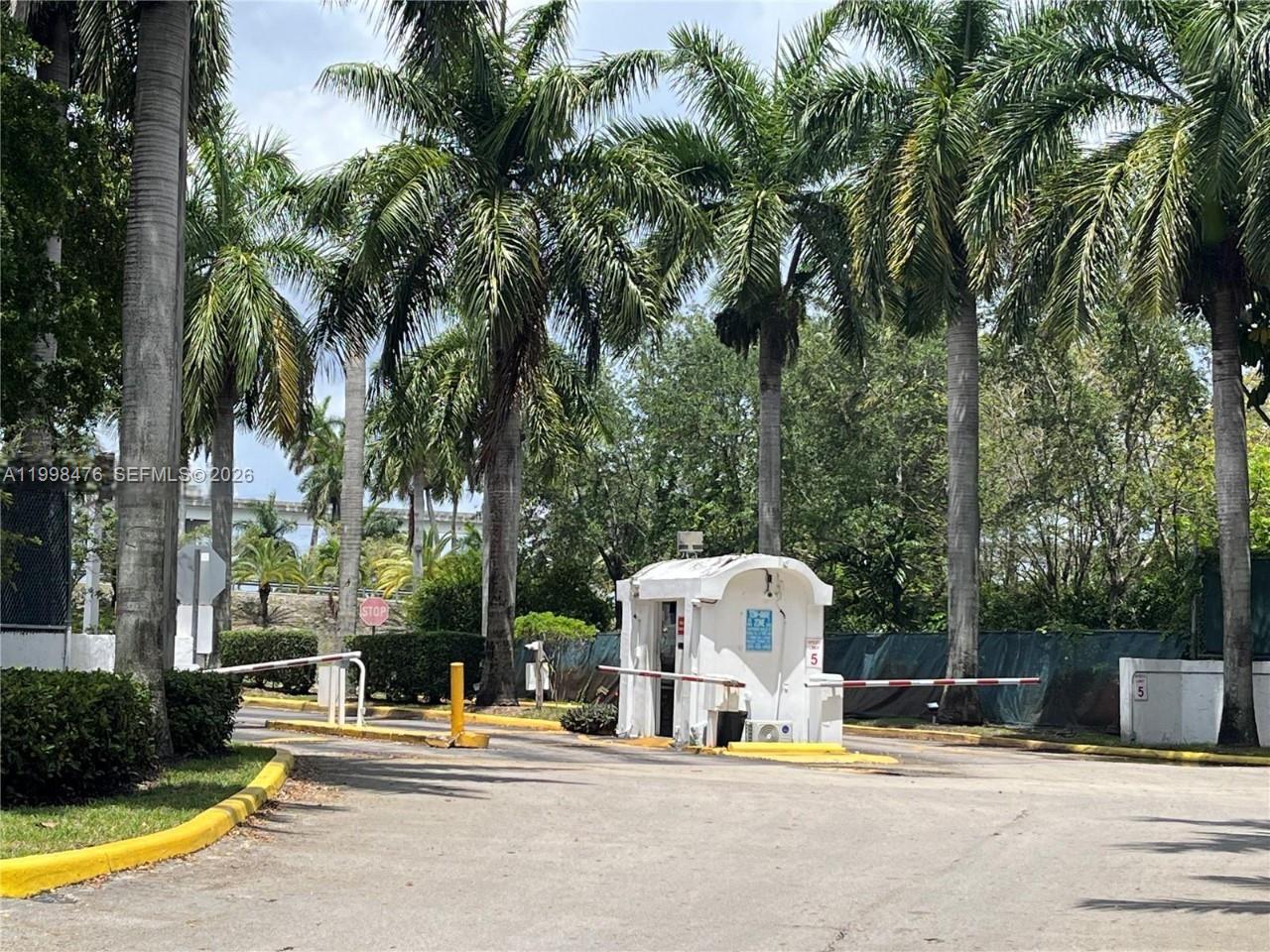 A gated entrance features a small white guard booth surrounded by tall palm trees — 494 NW 165th St Rd # 601, Miami FL 33169, MIAMI, FL