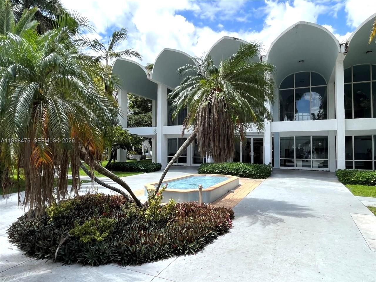 A modern building with arched rooflines features a small rectangular pool and palm trees — 494 NW 165th St Rd # 601, Miami FL 33169, MIAMI, FL
