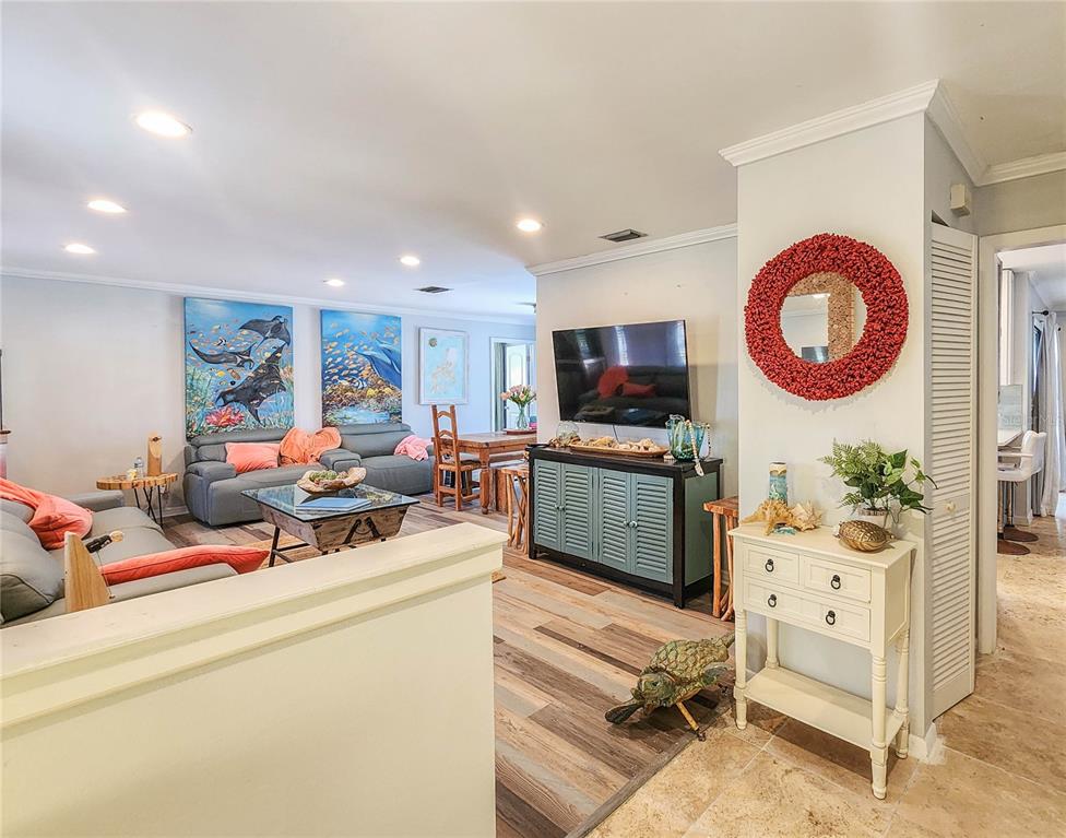 A living room with wood-look flooring, a blue media console, and coastal-themed wall art — 24 CLARIDGE COURT S, PALM COAST, FL