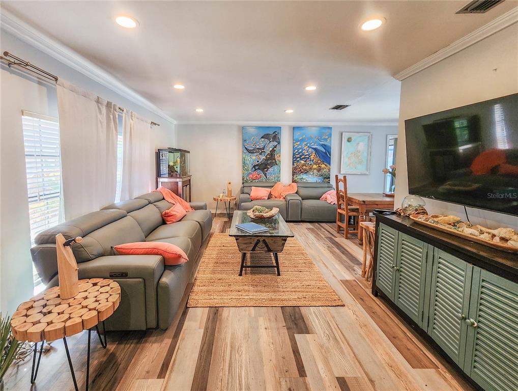 A living room features gray leather sofas, a wooden coffee table, and wood-look flooring — 24 CLARIDGE COURT S, PALM COAST, FL