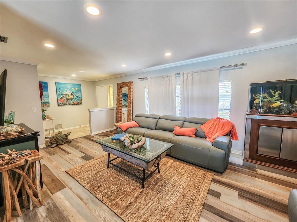 A living room features a gray sofa, a glass coffee table, and wood-look flooring — 24 CLARIDGE COURT S, PALM COAST, FL