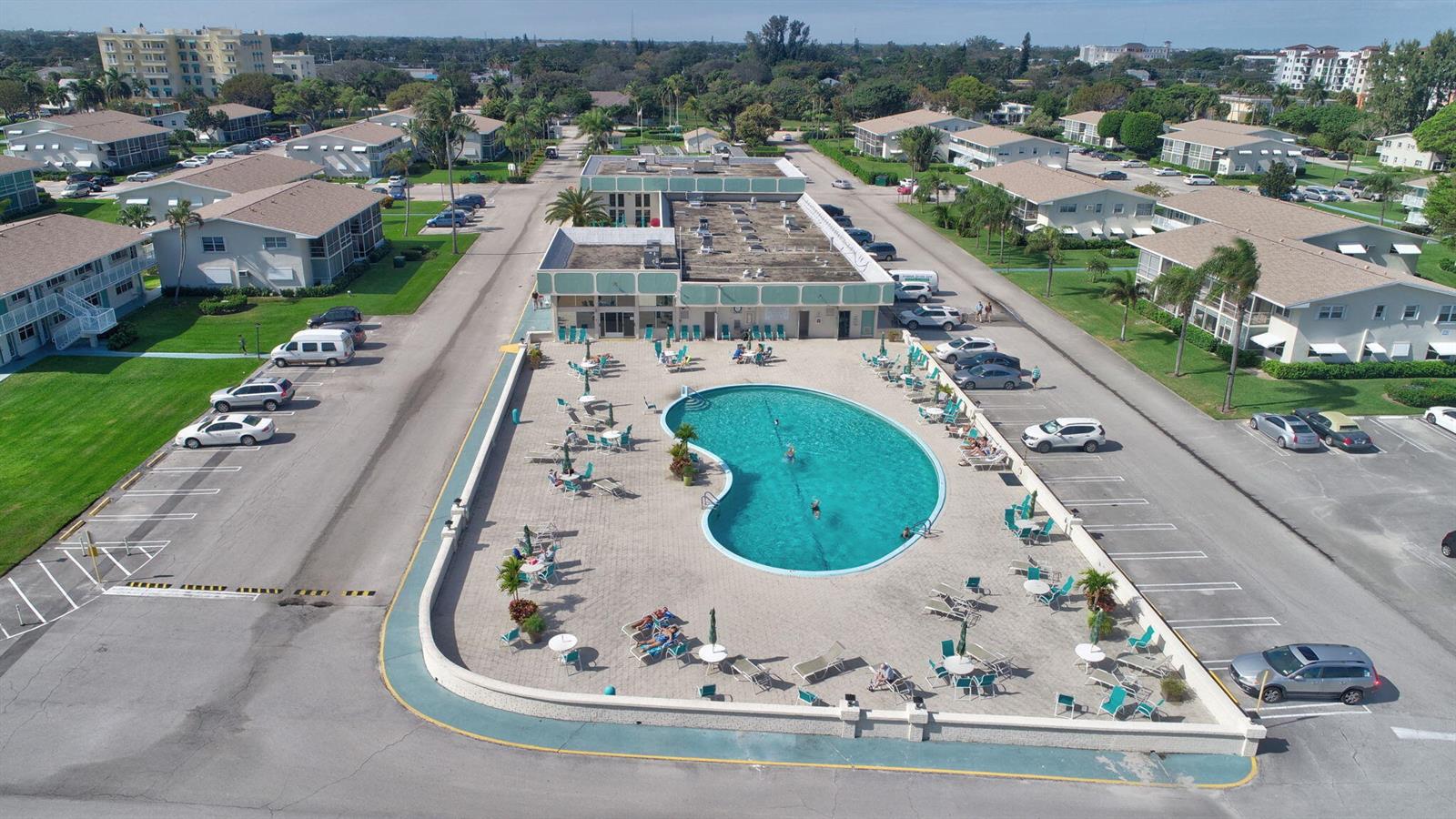 An aerial view shows a kidney-shaped swimming pool surrounded by a patio and parking lots — 850 E Horizons # 207, Boynton Beach FL 33435, BOYNTON BEACH, FL