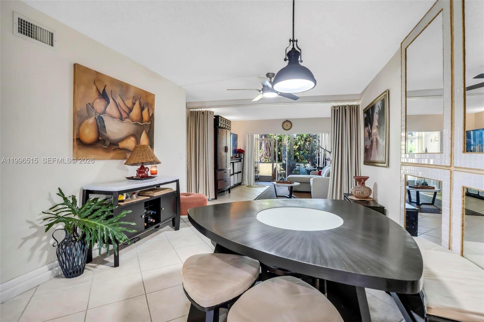 A dining area features a dark triangular table, tile flooring, and a large pear painting — 2300 SW 22nd Ave # 109, Delray Beach FL 33445, DELRAY BEACH, FL