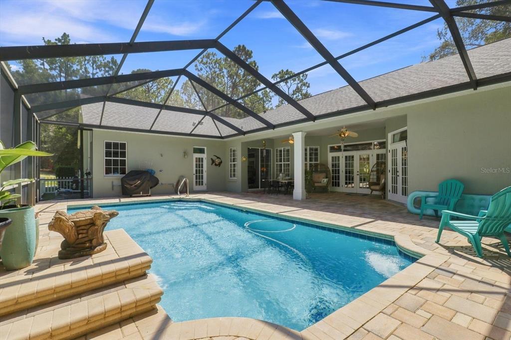 A screened-in patio features a swimming pool, stone pavers, and outdoor seating — 20257 SW 97TH PLACE, DUNNELLON, FL