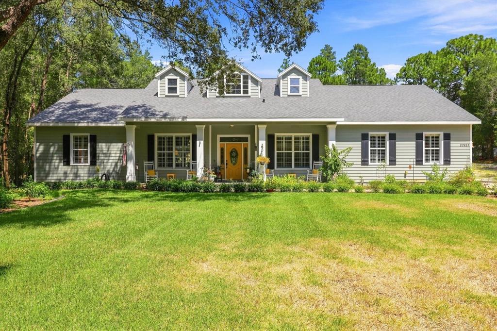 A single-story house with gray siding, a covered front porch, and three roof dormers — 20257 SW 97TH PLACE, DUNNELLON, FL