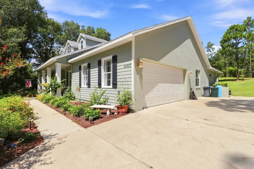 A light green house with a white garage door, a concrete driveway, and a front porch — 20257 SW 97TH PLACE, DUNNELLON, FL