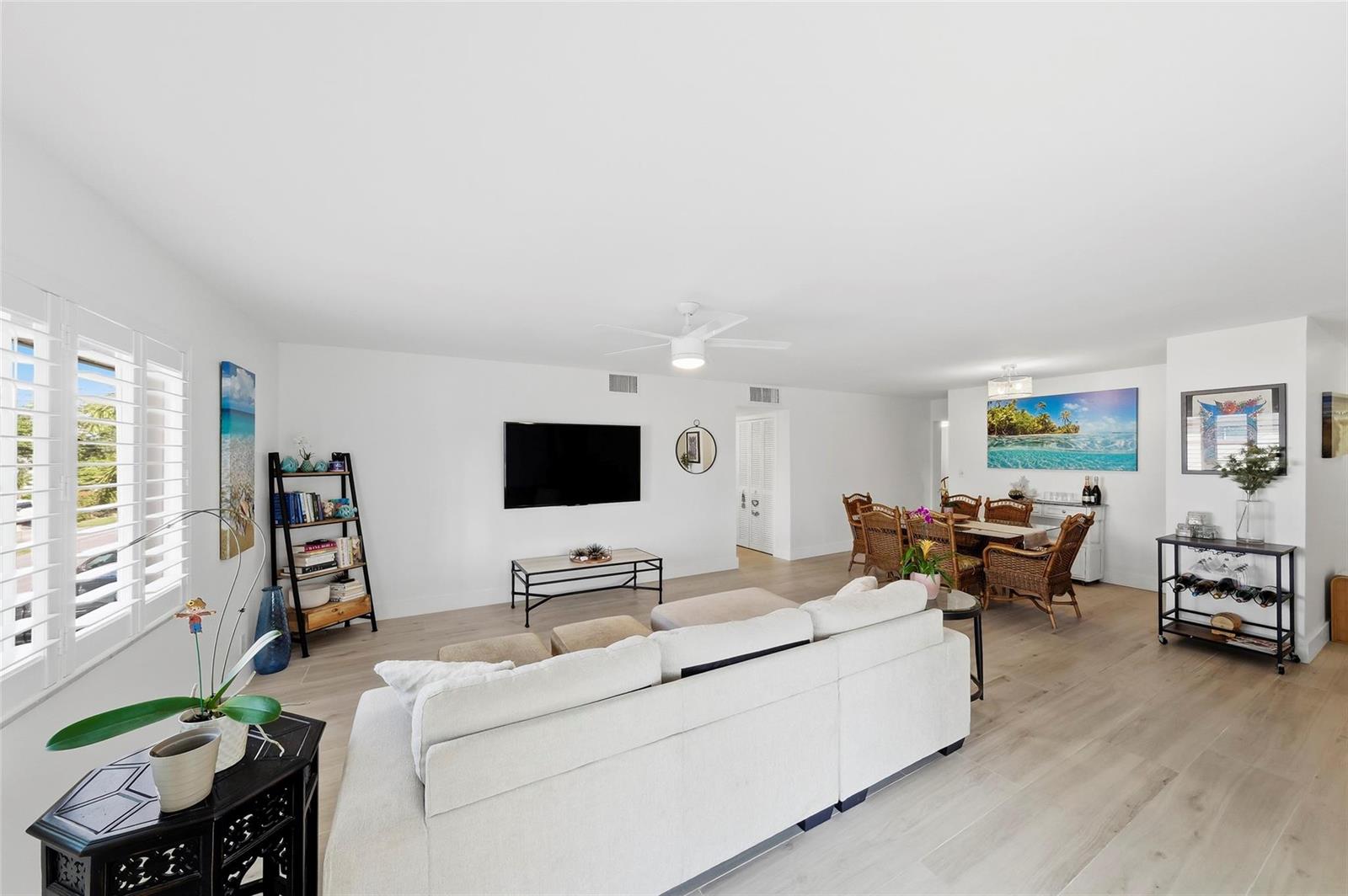 A bright living and dining area features white walls, light wood floors, and wicker furniture — 1450 N Riverside Drive # 201, Pompano Beach FL 33062, POMPANO BEACH, FL