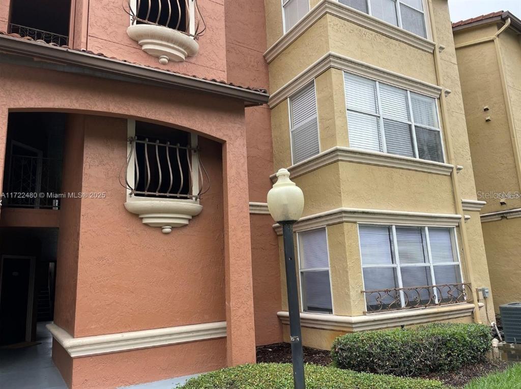 The exterior of a multi-story building features terracotta and yellow stucco walls with arched windows — 5160 CONROY ROAD UNIT 14, ORLANDO, FL
