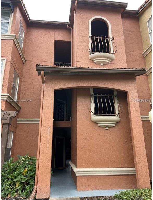 A multi-story stucco building exterior features arched balconies with metal railings and a covered entryway — 5160 CONROY ROAD UNIT 14, ORLANDO, FL