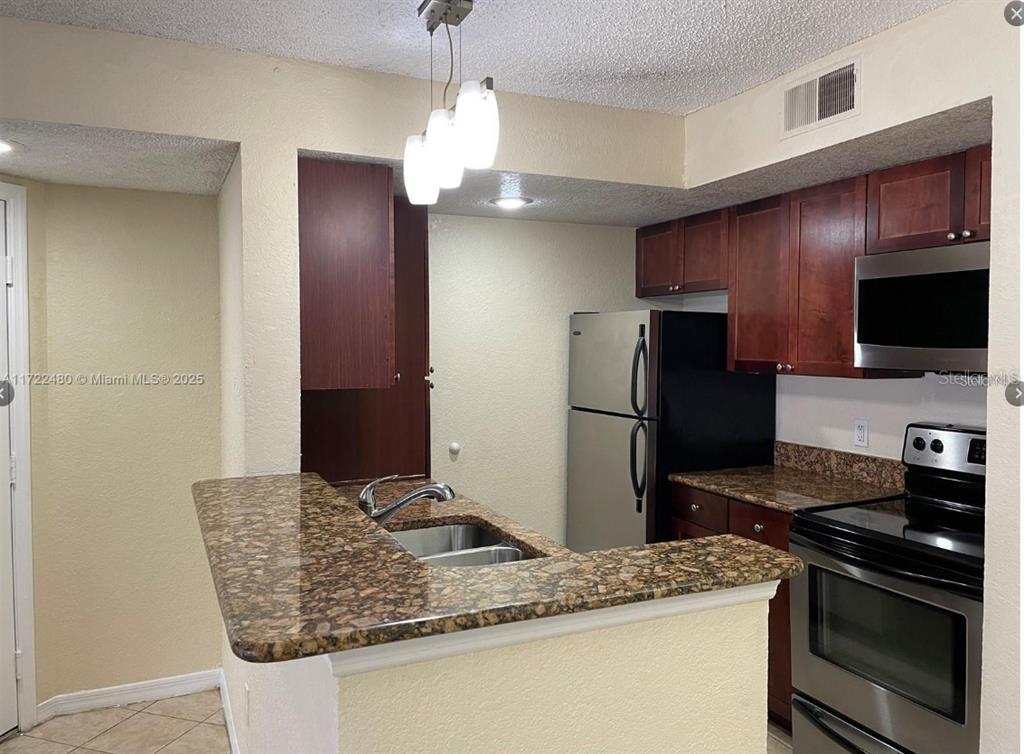 A kitchen features dark wood cabinets, granite countertops, stainless steel appliances, and a breakfast bar — 5160 CONROY ROAD UNIT 14, ORLANDO, FL
