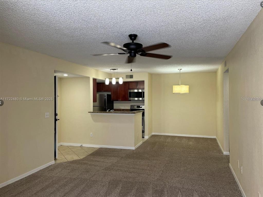 A living room with carpeted flooring, a ceiling fan, and an open kitchen with cabinets — 5160 CONROY ROAD UNIT 14, ORLANDO, FL