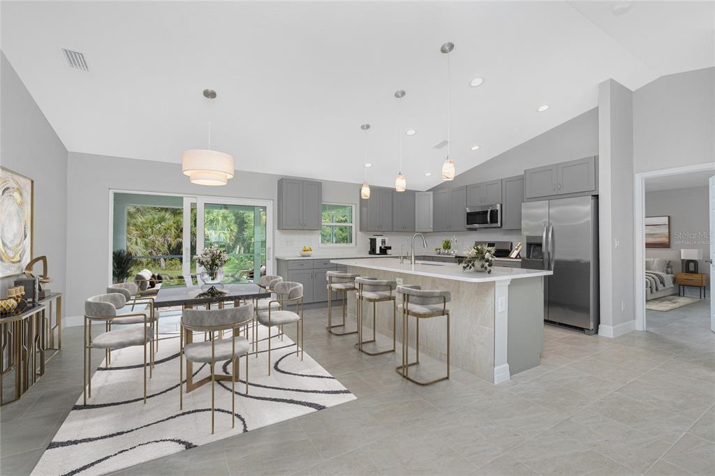 A modern kitchen and dining area feature gray cabinetry, a stone-front island, and tile flooring — 5208 CITRON ROAD, NORTH PORT, FL