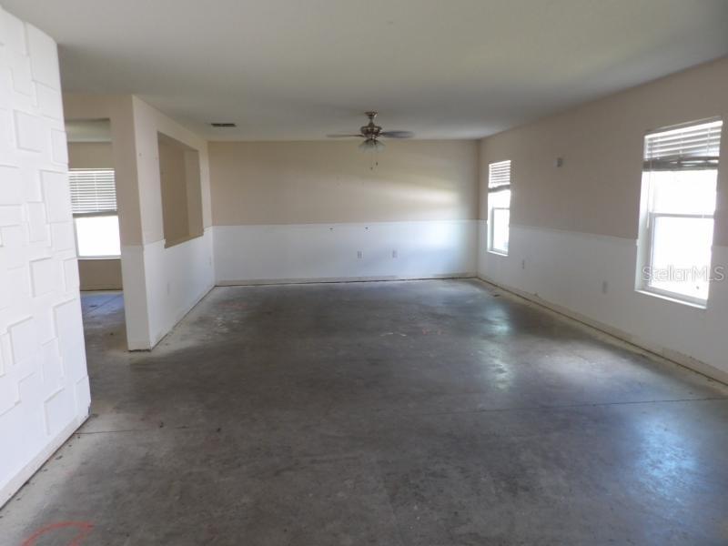 An empty room with concrete floors, white wainscoting, a ceiling fan, and two windows — 11301 BRIGHTON KNOLL LOOP, RIVERVIEW, FL